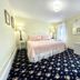 Quaker Inn in Ocean Grove guest room with pink bed, floral carpet, windows and lamps