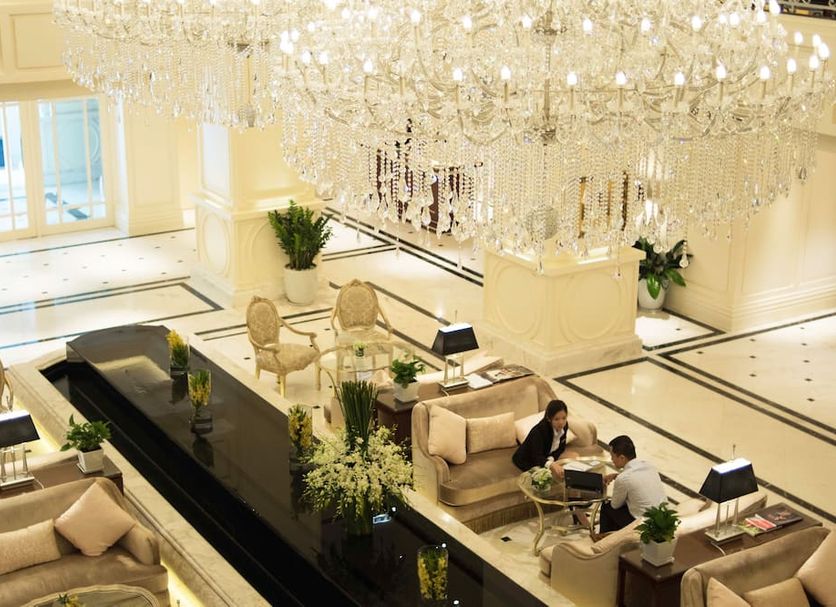 Apricot Hotel Hanoi lobby with grand chandelier, beige seating, and guests in a bright lounge