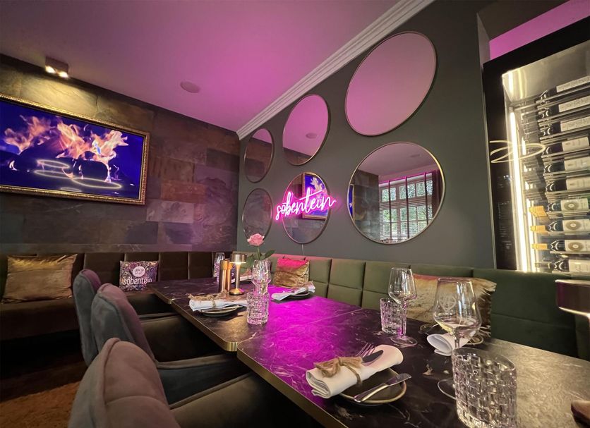 Hotel Am Schloss Ahrensburg lounge dining area with neon sign, mirrored wall accents, and set table