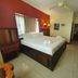 Caye Caulker Plaza Hotel guest room with king bed, ceiling fan, desk, and red accent wall in Caye Caulker