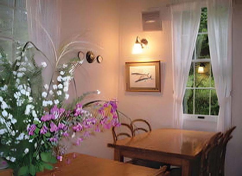 Pension Wave Inn in Itō dining room with wooden tables, flowers, wall art and garden-view window