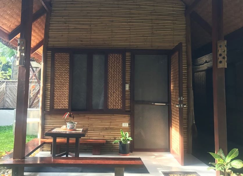 Le Cou de Tou Village Resort in Roxas with a shaded wooden porch, table, bench and potted plants