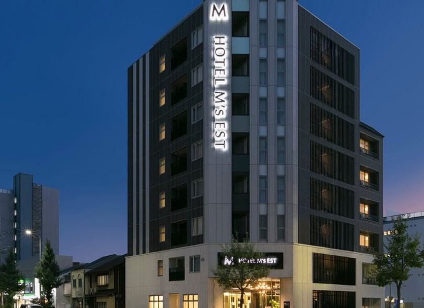 Hotel M's Est Kyoto Station South in Kyoto, exterior at dusk with illuminated sign on a tall modern building
