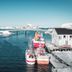 Sommarøy Arctic Hotel Tromsø waterfront harbor with boats, bridge, and snowy shoreline in Sommarøy