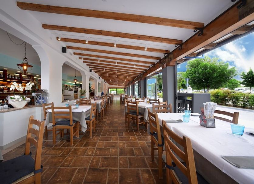 Alla Pergola in San Michele al Tagliamento: covered outdoor dining terrace with wooden tables and open-air view