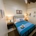 Waterside Inn in Vieques guest room with iron bed, blue bedding, bedside lamps, and wall art