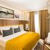 Hotel Eiffel Turenne in Paris guest room with double bed, mustard throw, desk and curtain-covered window