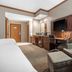 Norfolk Lodge & Suites, an Ascend Collection Hotel room with desk, armchair, TV, and ottoman in Norfolk