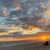 Sunset beach view at Hostel Dos Gringos in Maricá, with people sitting on the sand.