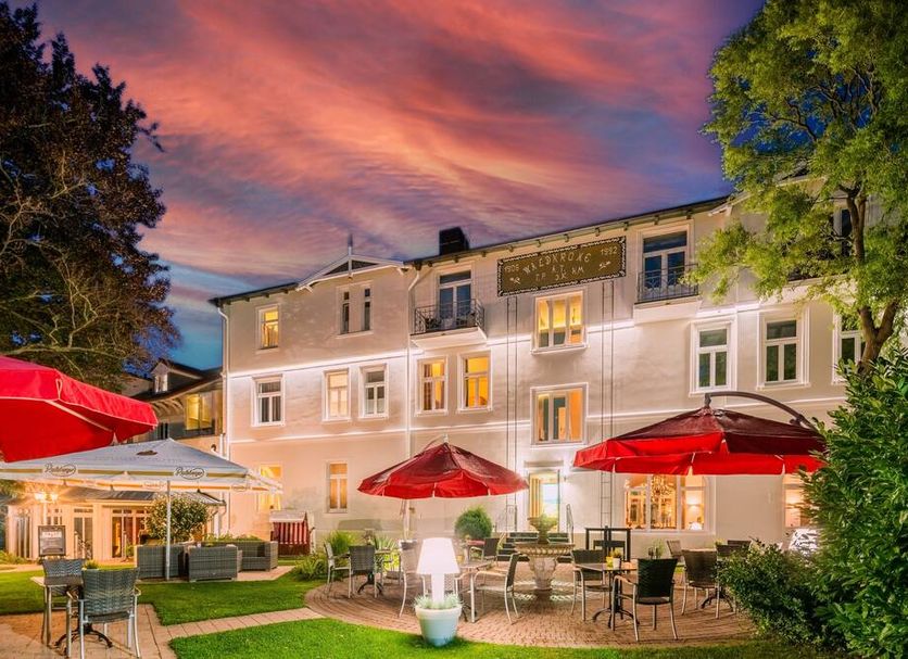 Hotel Residenz Waldkrone Kühlungsborn exterior with red umbrellas and terrace at dusk in Kuehlungsborn