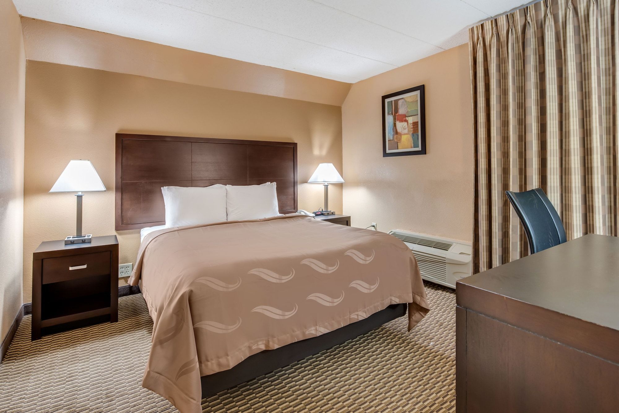 Quality Inn & Suites Cincinnati Uptown Norwood guest room with king bed, nightstands and desk