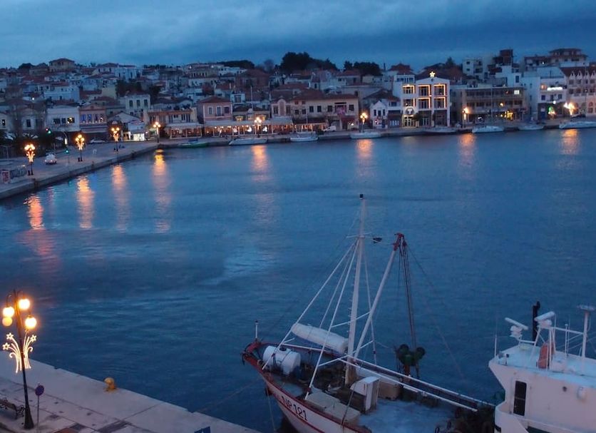 Lesvion Hotel in Mytilene overlooking a harbor at dusk with boats and waterfront lights