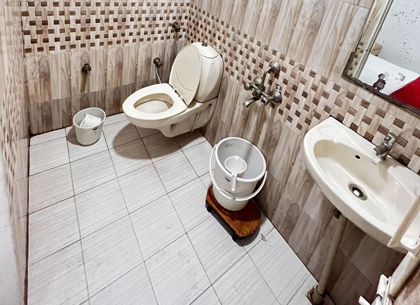 Stayguru Usha Residency, Bhuj: compact tiled bathroom with toilet, sink, mirror, shower and water heater