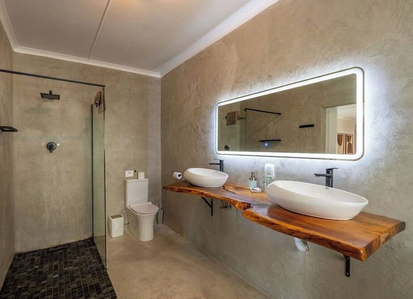 Chestnut Country Lodge in Kiepersol bathroom with walk-in shower, toilet, twin vessel sinks and backlit mirror.