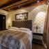 Det Hanseatiske Hotel Bergen bedroom with tufted headboard, patterned wallpaper and wood ceiling