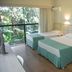 Hotel Nacional Inn Foz do Iguaçu room with three beds and a balcony view of lush tropical greenery
