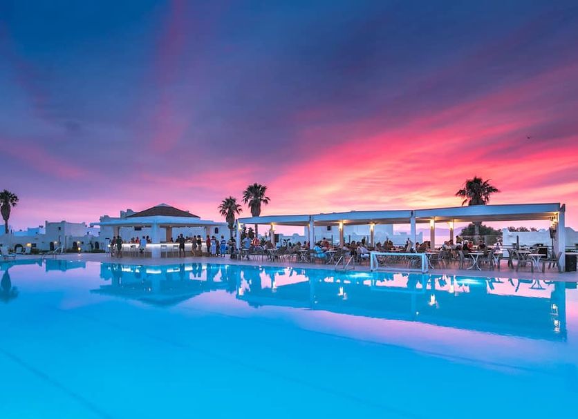 The Aeolos Beach Hotel in Kos with a lit pool at sunset and palm trees by the water