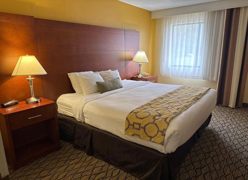 Baymont by Wyndham Mishawaka South Bend Area room with king bed, lamps and window in Mishawaka