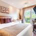 Pousada Grandchamp - Campos do Jordao guest room with king bed, window view, and desk in Campos do Jordão