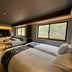 Hotel Obokekyo Mannaka guest room in Miyoshi with twin beds, sofa, and large forest-view windows