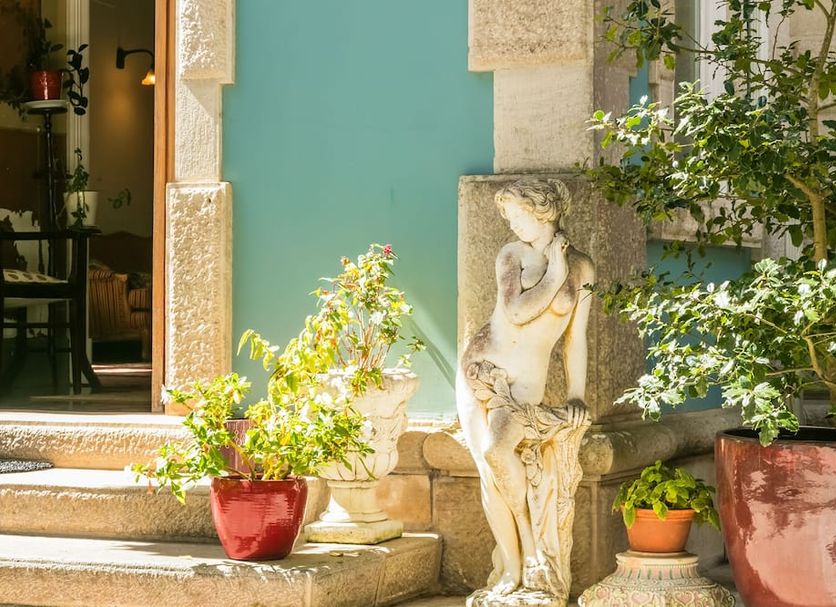 Chalet Saudade in Sintra courtyard with potted plants and a stone statue by the entrance