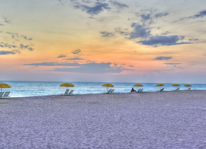Sunset Vistas Beachfront Suites in Treasure Island: beach at sunset with yellow umbrellas and lounge chairs