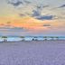 Sunset Vistas Beachfront Suites in Treasure Island: beach at sunset with yellow umbrellas and lounge chairs