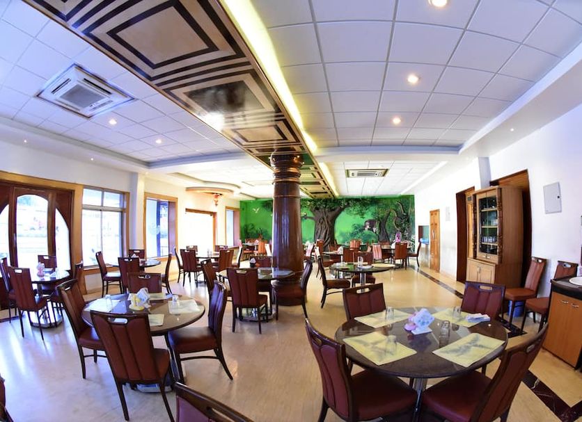 Hotel Sharada International in Udupi dining room with round tables and wooden chairs