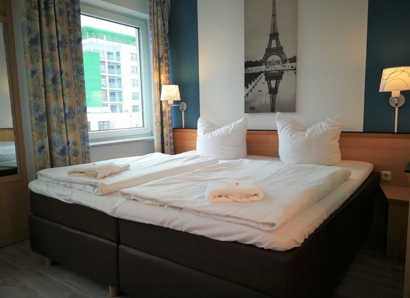 Hotel Near By in Laatzen: double bed with Eiffel Tower wall art and window view in a guest room