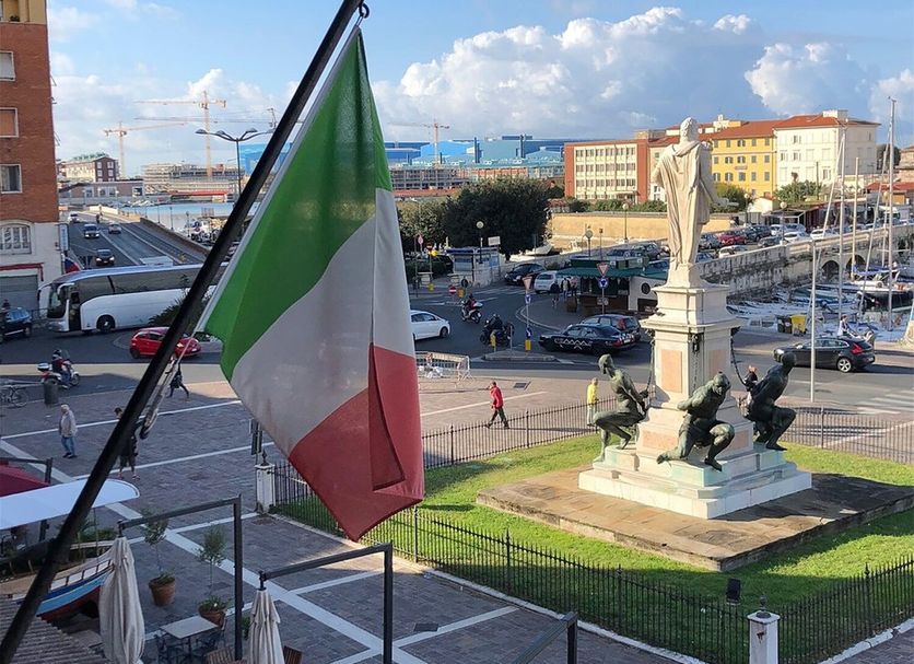 Hotel Gran Duca in Livorno overlooking harbor square with Italian flag and monument