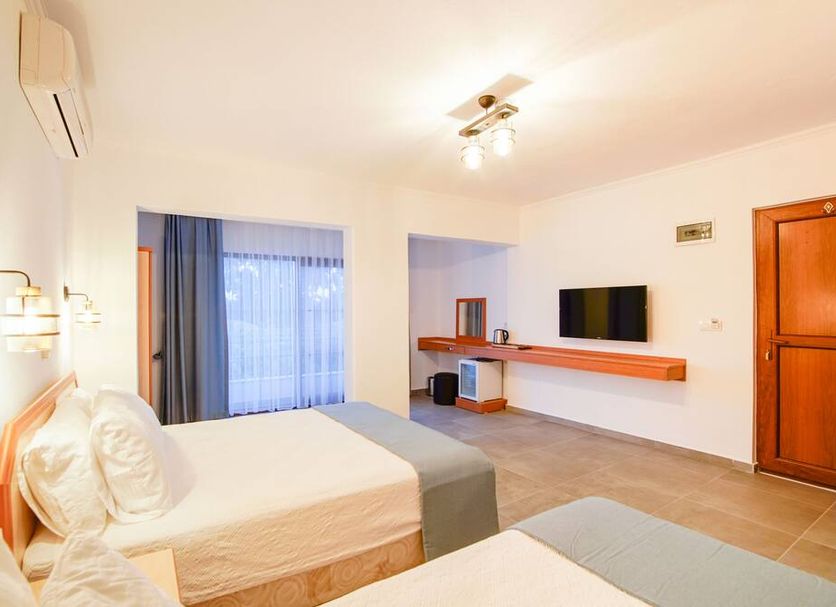 Ova Butik Otel in Mesudiye guest room with two beds, wall-mounted TV, and balcony door