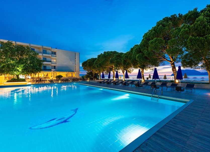 Porto Rio Hotel in Río with a lit outdoor pool, loungers and sea views at dusk