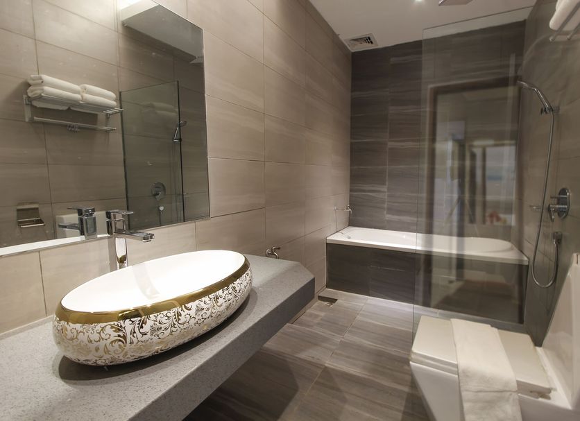 Lavigo Resort Langkawi bathroom with vessel sink, bathtub, glass shower and tiled walls