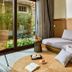 M Village Phu Quoc guest room with large garden-view window, desk, and daybed seating