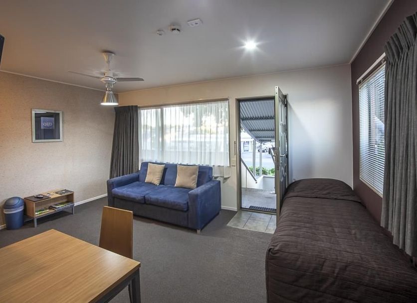 Landmark Manor Motel in New Plymouth room with sofa, bed, and open door to outdoor area