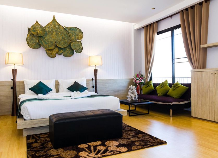 Panlaan Boutique Resort in Nong Khai guest room with king bed, seating nook, lamps and wall art