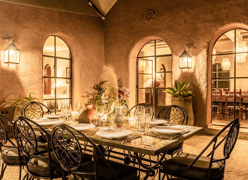 Le Jardin Des Douars in Essaouira: warm courtyard dining area with arched windows and wrought-iron chairs