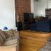 The Macaw Guesthouse in New York living area with raised wood floor, navy sofa, brick wall and staircase