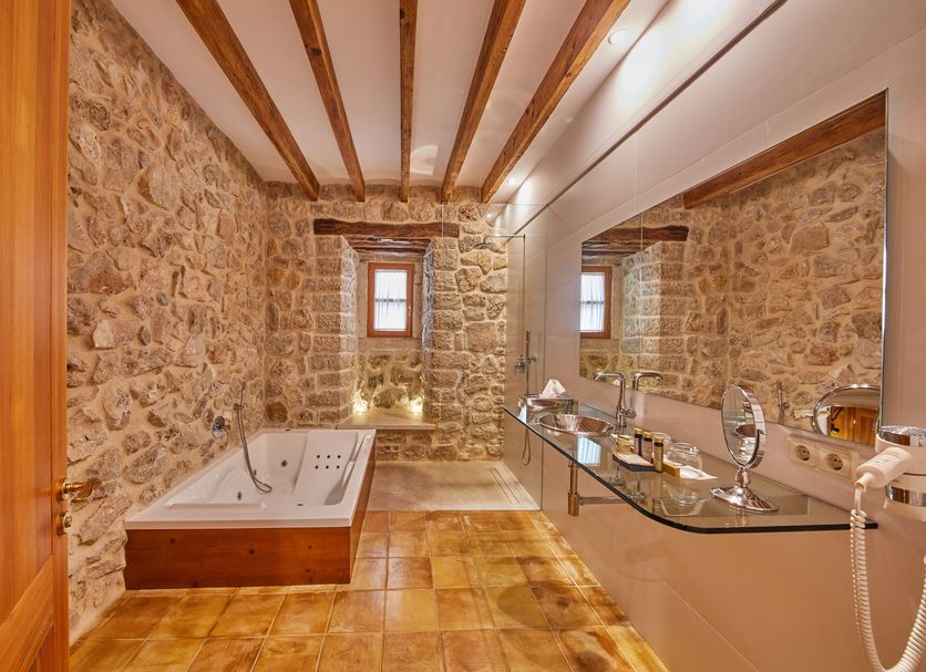 Cas Comte Petit Hotel & Spa - Adults Only spa bathroom with stone walls, soaking tub and glass vanity in Lloseta