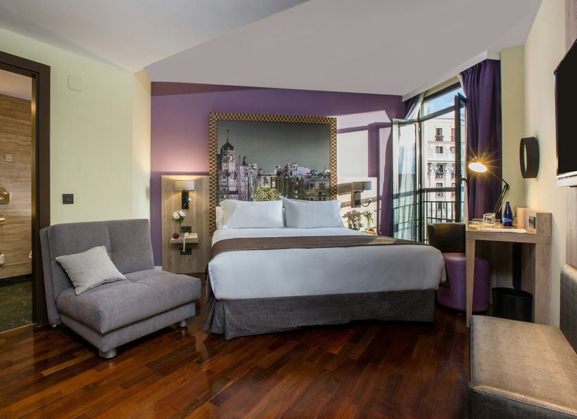 Leonardo Hotel Madrid City Center room with king bed, balcony city view, armchair and desk in Madrid
