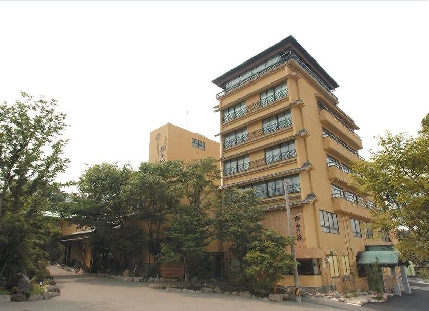 Motoyu No Yado Kurodaya in Beppu, a multi-story hotel building surrounded by trees and a driveway