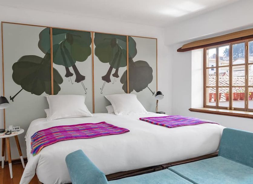 Andenes Cusco guest room with twin bed, tropical headboard art and window bench