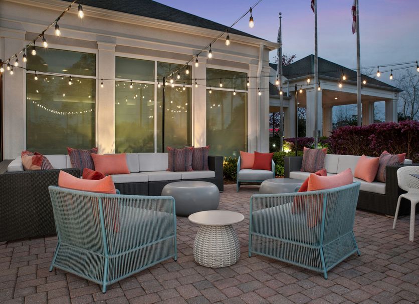 Hilton Garden Inn Tallahassee Central patio with string lights, lounge seating and fire pit at dusk