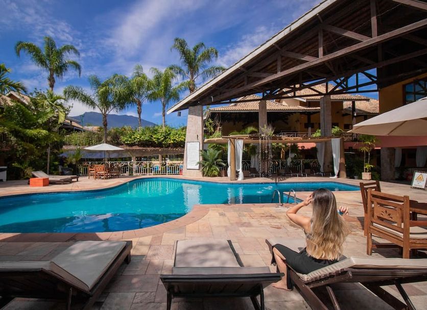 Ilha Flat Hotel in Ilhabela with a tropical outdoor pool, palm trees, and sun loungers by the deck.