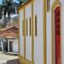 Hospedagem Central in Tiradentes with a yellow-trimmed white facade on a cobblestone street