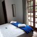 Pousada Ilha Morena in Florianopolis bedroom with a bed, wardrobe, mirror and balcony door to greenery.