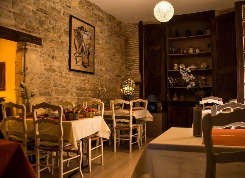 Hotel Raymond Vii in Albi dining room with stone walls, wood chairs, and table settings