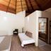 Blue World Dharavandhoo guest room with vaulted wood ceiling, twin beds, and open bathroom doorway