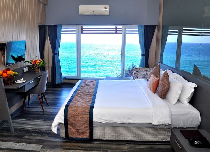Sinclairs Bayview in Port Blair with a king bed and desk overlooking the ocean through large windows