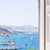 Rhenia Hotel in Tourlos with a view of blue bay waters, boats, and a coastal hillside